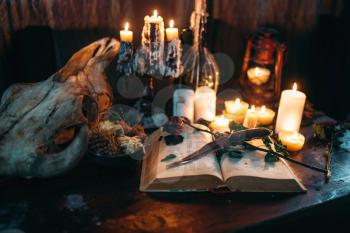 Witchcraft, dark magic, candles with ritual book on the table, nobody. Occult and esoteric symbols