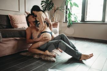 Sexy couple makes love on the floor against a couch, erotica. Erotic scene, sexual relationship