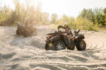 Two atv riders in helmets ride in a circle on sand, offroad in forest. Riding on quad bike, extreme sport and travelling, quadbike summer adventure