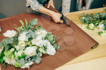 Female florist hands cuts flower decoration with scissors. Floral business, bouquet preparation process