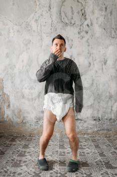 Funny freak man in diaper wrapped in packaging film, grunge room interior. Mad male person in abandoned house, crazy guy