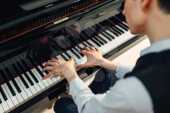 Pianist playing music on grand piano, back view. Musician practicing melody at the royale, classical musical instrument