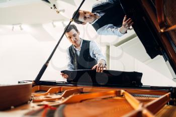Male pianist sets the grand piano before the performance of a musical composition. Musician adjusts royale, classical musical instrument tuning