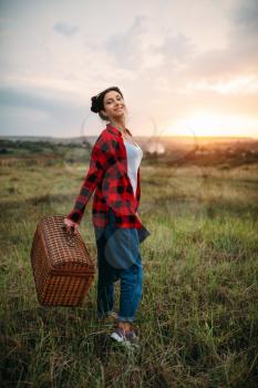 Pretty woman with basket, picnic in summer field. Romantic junket, happy weekend