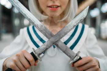 Anime style blonde girl with two swords, cute lolita. Cosplay fashion, asian culture, doll with blade, pretty woman with makeup