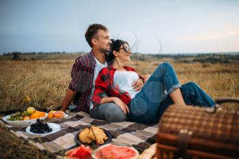 Love couple, picnic on plaid in summer field. Romantic junket of man and woman