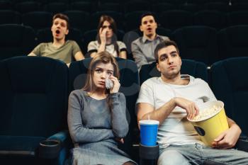 Couple with popcorn in cinema. Boring film concept, people watching movie