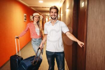 Happy couple with suitcases checking into the hotel. Travelling or tourism concept