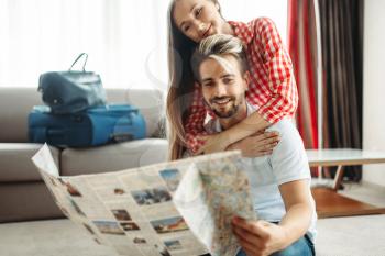 Young couple studying a map before summer journey. Fees on vacation concept. Preparation for summer holidays