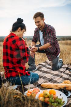 Man makes a marriage proposal on romantic picnic in summer field. Junket of man and woman, happy moments