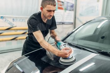 Male person with polishing machine prepares to restore the paint of car. Auto detailing on carwash station