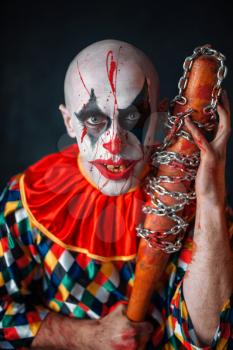 Crazy bloody clown with baseball bat. Man with makeup in halloween costume, maniac