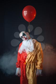 Mad bloody clown with makeup in carnival costume hung himself on air balloon, crazy maniac, scary monster