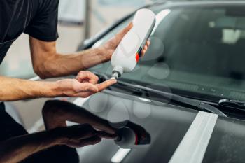 Male person with car polishing paste. Auto detailing on carwash station, restore the paint of vehicle