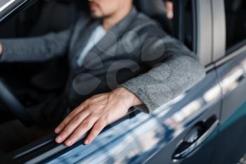Male person sitting in new car, showroom. Customer choosing vehicle in dealership, automobile sale, auto purchase