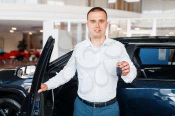 Manager gives key to the new car in showroom. Male customer buying vehicle in dealership, automobile sale, auto purchase