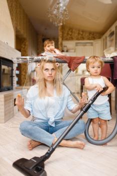 Young housewife and kids practice yoga at the ironing board. Woman with children leisures at home together. Female person with daughter and son having fun in their house