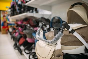 Many baby strollers on shelf in store closeup view, nobody, goods for newborns. Pushchair variety in shop