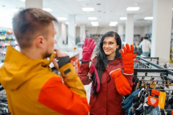 Couple choosing gloves for ski or snowboarding, sports shop. Winter season extreme lifestyle, active leisure store, customers with protect equipment
