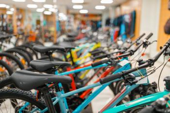 Rows of mountain bicycles in sports shop, focus on seat, nobody. Summer active leisure, showcase with bikes, cycle sale