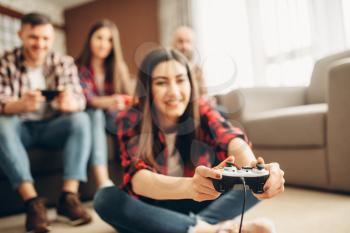 Smiling friends with joysticks plays tv console at home. Group of gamers with joypads playing videogame, male and female players with gamepads