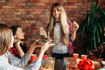 Female university student gets a sweet gift from her friends. Youth at the table in the flat, home party, birthday celebration