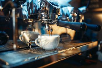 Espresso machine pours fresh black coffee into the cup closeup, nobody. Professional restaurant, cafe or cafeteria business equipment