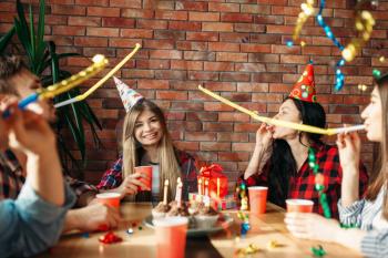 Group of highschool students celebrating the delivery of the session. Youth in clown caps at the table in the flat, home party