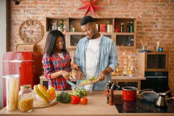 Black love couple cooking romantic dinner on the kitchen. African family preparing vegetable salad at home. Healthy vegetarian lifestyle