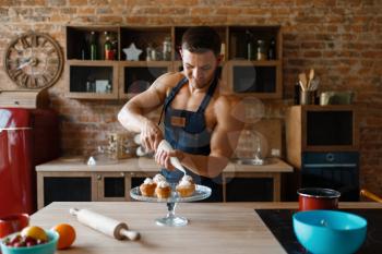 Nude man in apron cooking dessert on the kitchen. Naked male person preparing breakfast at home, naked food preparation