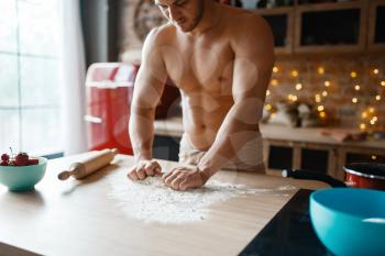 Muscular husband in underwear cooking on the kitchen. Naked man preparing breakfast at home, food preparation without clothes
