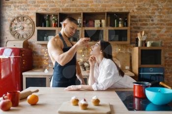 Attractive love couple in underwear cooking on the kitchen together. Naked man and woman preparing breakfast at home, food preparation without clothes