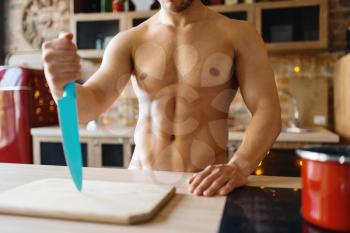 Man with naked body cooking on the kitchen. Nude male person preparing breakfast at home, food preparation without clothes