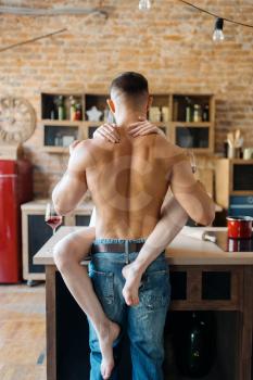 Sexy couple hugs on kitchen counter, romantic dinner. Man and woman preparing breakfast at home, food preparation with elements of eroticism
