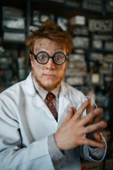 Crazy male scientist in glasses working in laboratory. Electrical testing tools on background. Lab equipment, engineering workshop