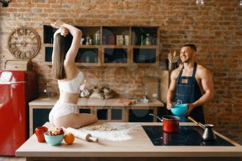 Sexy couple in underwear cooking on the kitchen. Naked man and woman preparing breakfast at home, naked food preparation