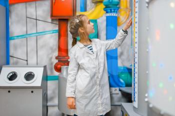 Little child in uniform playing doctor in laboratory, playroom. Kid plays medicine worker in imaginary hospital lab, profession learning, childish dream