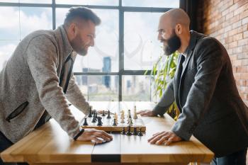 Chess players look into each other's eyes. Two chessplayers finished intellectual tournament indoors. Chessboard on wooden table