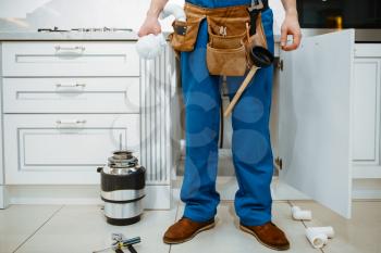 Male plumber installing water filter in the kitchen. Handywoman with toolbag repair sink, sanitary equipment service at home