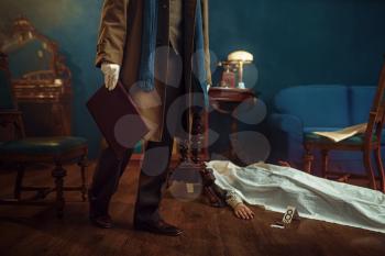 Male detective in coat holds leather folder, victim under the cape at the crime scene, retro style. Criminal investigation, inspector is working on a murder, vintage room interior on background