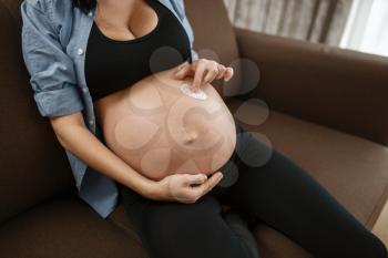 Pregnant woman with belly relaxing on couch at home. Pregnancy, calm in prenatal period. Expectant mom resting in bedroom, healthy lifestyle