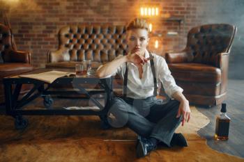 Woman in strict clothes relax on the floor with whiskey and cigar, retro fashion, gangster style