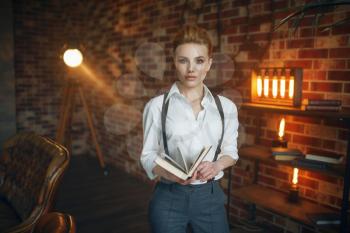 Business woman in strict clothes poses with book in studio, retro fashion, gangster style. Vintage lady in office with brick walls