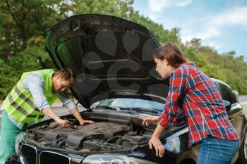 Young couple at the opened hood on road, car breakdown. Broken automobile or emergency accident with vehicle, trouble with engine on highway