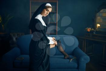 Sexy nun in a cassock puts on stockings with lace, vicious desires. Corrupt sister in the monastery, sinful religious people, attractive sinner