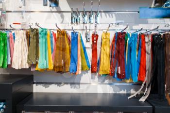 Colorful zippers on shelf in textile store, nobody. Showcase with acessories for sewing, clothing choice in shop