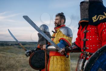 Medieval knights with swords and axe poses in armour, great fighter. Armored ancient warriors in armor posing in the field