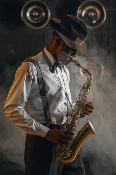 Black jazzman plays the saxophone on the stage with spotlights. Black jazz musician preforming on the scene