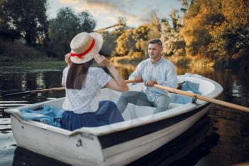 Love couple boating on lake at summer day. Romantic data, boat ride, man and woman walking along the river