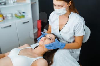 Cosmetician in gloves and female patient on treatment table. Rejuvenation procedure in beautician salon. Doctor and woman, cosmetic surgery against wrinkles